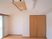 大きなクローゼットが付いたフローリングの部屋には大きなエアコンと窓があり、窓にはカーテンが付いていない。