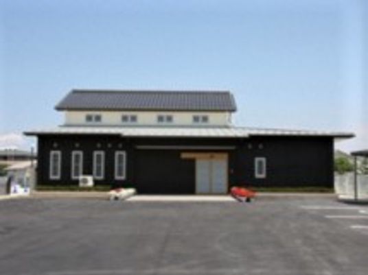２階建ての建物の外観写真。手前に駐車場スペースがある広めの敷地