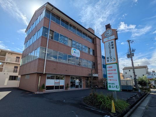 オレンジと黄色、黒という大胆な色使いの2階建ての建物。各フロアにベランダもある。