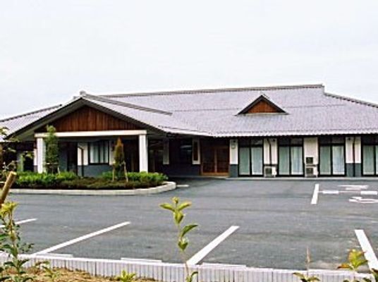 天井の高い平屋建ての建物が広い敷地内に建っていて、駐車場もある。玄関には三角屋根が付いている。