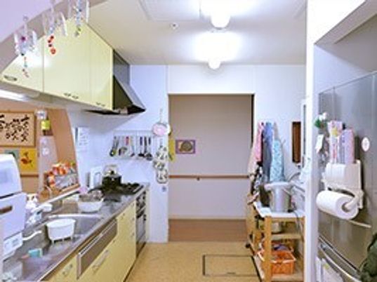 家庭的なサイズのキッチンスペースを写した写真。手すりが付いている廊下が見えている