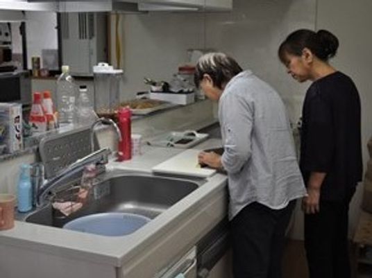 生活リハビリの一環で料理に取り組んでいる高齢者とそれを見守るスタッフ