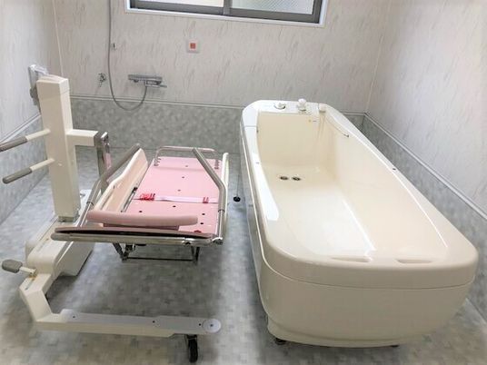 寝たまま入浴可能な寝台浴を設置した、日当たりのいい浴室。呼び出しボタンやシャワーもある。