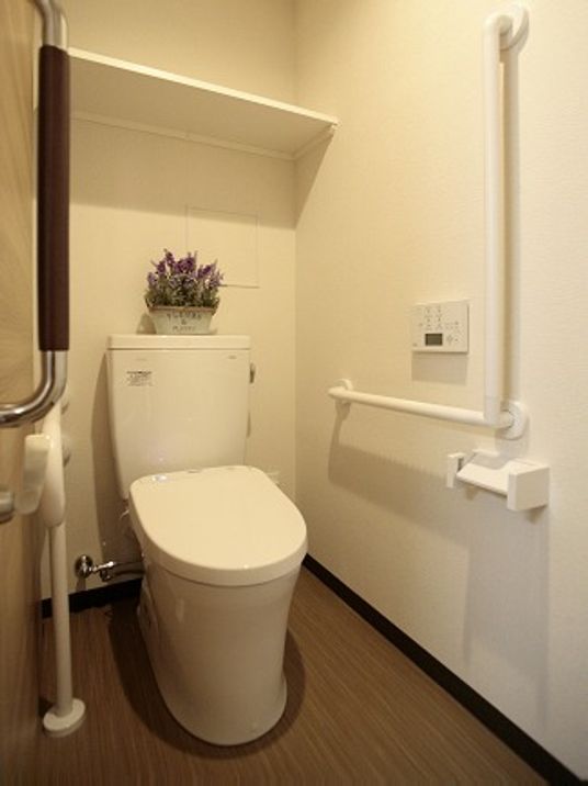 L字型の手すりが付いている広めのトイレ。白を基調にしている清潔感のあるトイレ