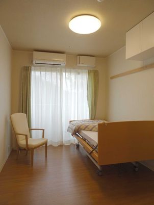 ベッドと小さな椅子が置いてあるワンルームタイプの部屋の様子