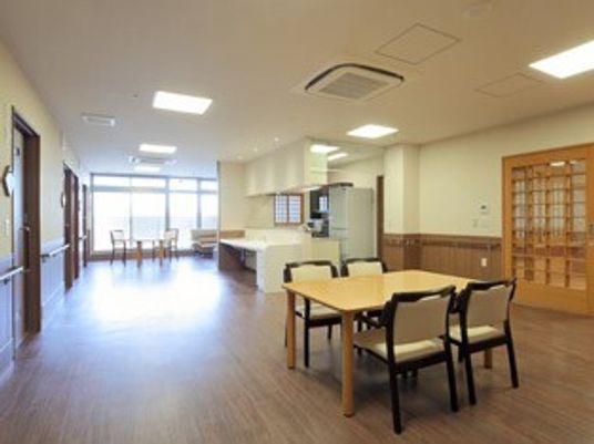 広めのフローリングフロアにイスとテーブルが置いてある様子。施設内のリビングスペース
