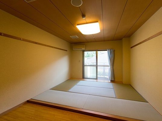 畳敷きの和室には和風の照明が付き、大きな窓にはカーテンが設置され、手前には床間もある。