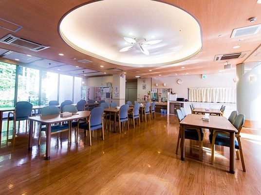 青い椅子がセットされたダイニングテーブルが複数並んだ食堂には大きな窓があり、照明も付いている。