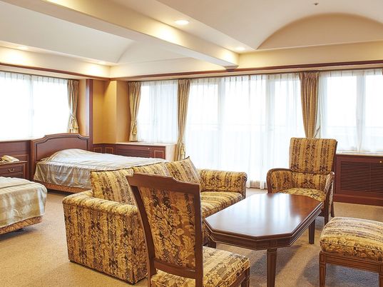 ホテルのような雰囲気の施設内の居室スペース。柄が入ったソファや椅子が置いてある