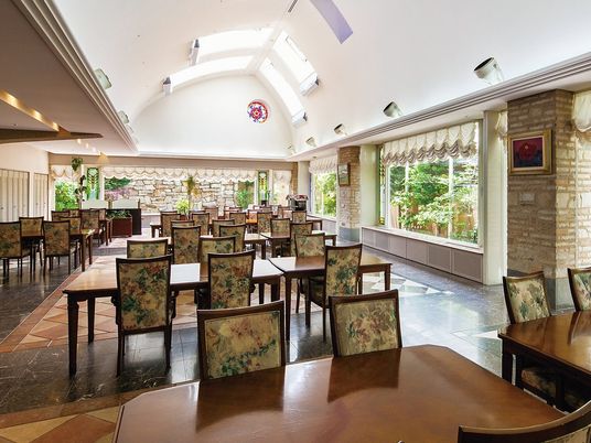 柄の入ったソファや天井の高い空間が印象的な写真。奥のほうに中庭が見えている