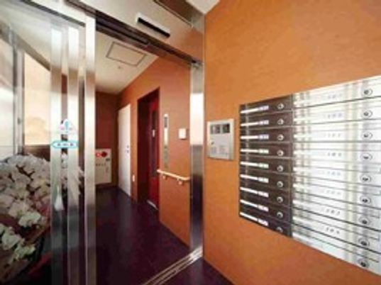 マンション風の施設のエントランス・アプローチ付近。ポストがある様子が分かる写真
