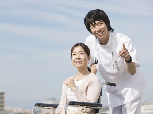 車椅子のご入居者様とサポートするスタッフ