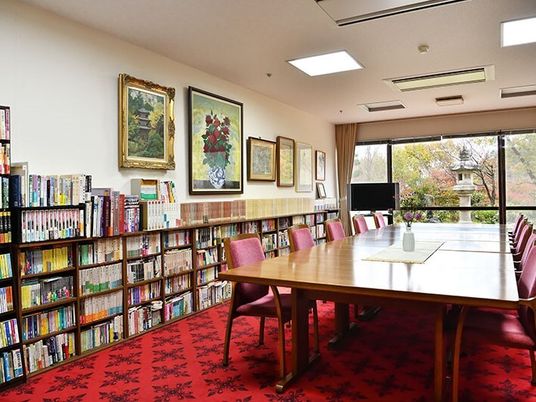 壁際にはたくさんの本が並べられた本棚があり、絵画が飾られ、中央にはテーブルセットが置かれている。