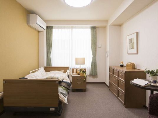 洗面台とトイレ付きの部屋に介護用ベッドなどが置かれている様子