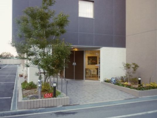 エントランス周辺には木や花が植えられ、エントランス横のガラスからは中の様子をうかがうことができる。
