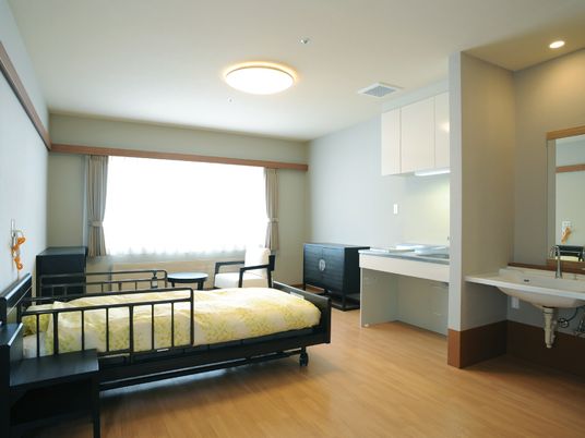 ベッドや洗面台、机などが置いてあるワンルームの様子。高齢者用の設備