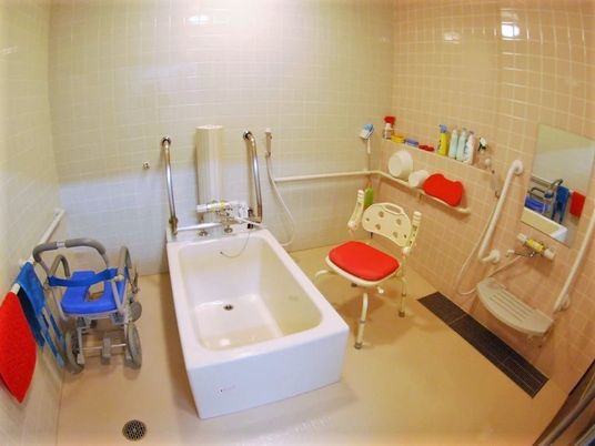 洗い場が広い浴室には白い個浴槽と浴室用車いすやシャワーチェア、シャワーがある。