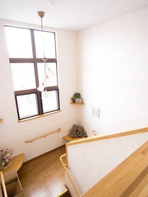 白い壁にフローリングの床。階段の踊り場にはセンスのいい花や小物が飾られている。