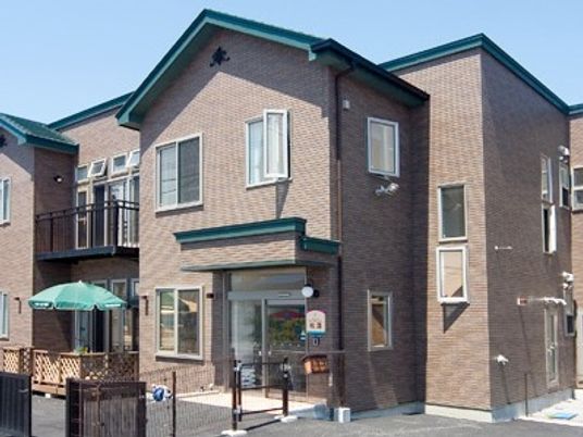 ブラウン系の2階建ての建物は家庭に近い雰囲気。三角の屋根が付き、テラスもある。