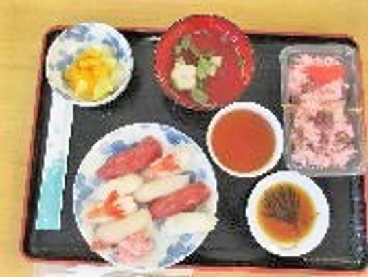 握り寿司や赤飯がずらりと並んだ黒いトレー。