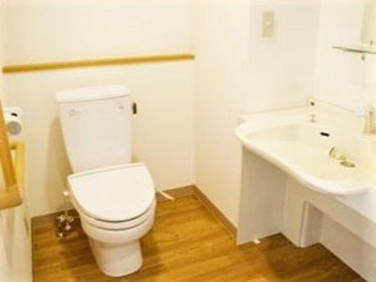 フローリングの広いトイレには手すりや手洗い場が付いている。