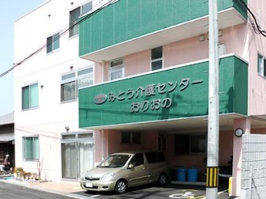 「みとう介護センターおりおの」と書かれた3階建ての建物。１階部分には駐車スペースがある。