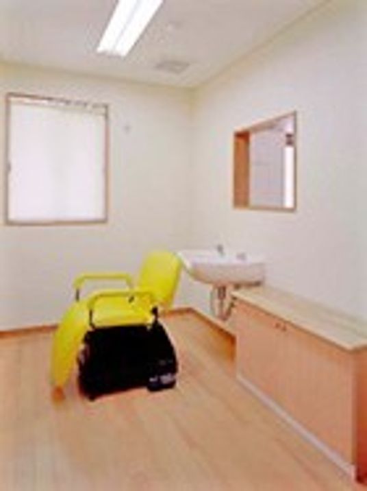 黄色い美容室用の椅子が設置されたスペースには洗髪台も設置されている。