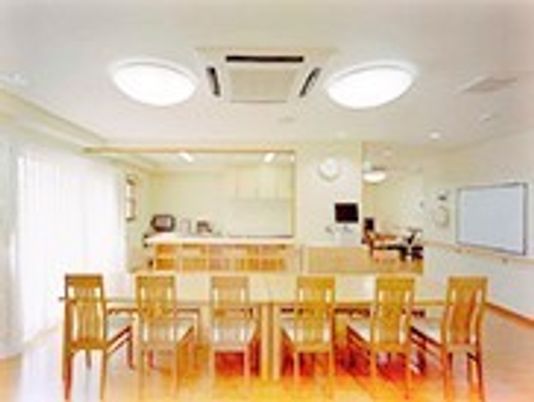 木製のダイニングテーブルが設置され、テレビもあり、大きな窓からは明るい日差しが降り注いでいる。
