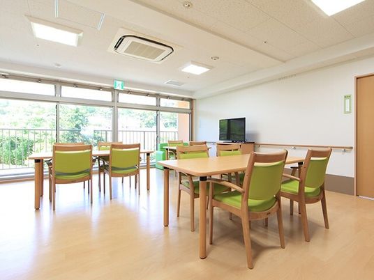 大きな窓がある施設内のリビングスペース。四人掛けのテーブルと椅子が並べられている様子