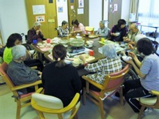 なべを囲んで食事を楽しんでいる入居者とスタッフ。