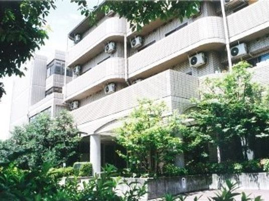4階建ての建物は白を基調としていて、周辺には緑があふれている。
