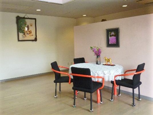 絵画がかかる壁と椅子・テーブルが写っている写真。広めの応接間のような場所