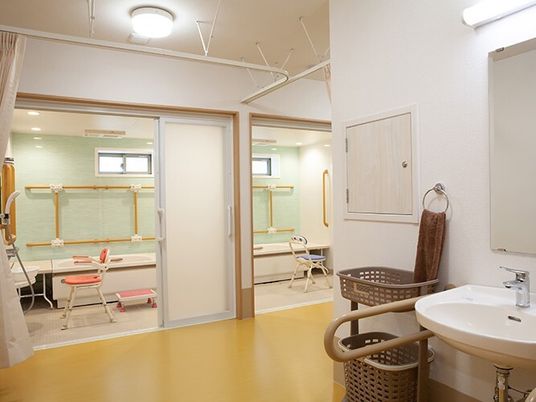 一人用の浴槽が置かれた浴室が二つ並び、脱衣所にはカーテンが付いている。。手すりやシャワー、シャワーチェアも設置されている。