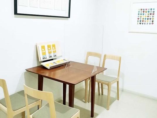 4人掛けのテーブルセットが置かれ、壁には絵画が飾られている。テーブルの上にはアクリル板がある。
