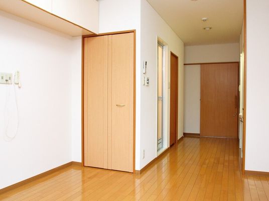 クローゼットや緊急通報装置があり、家具などは置かれていないフローリングの部屋。