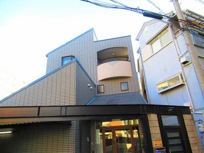 3階建ての建物はブラウン系で玄関には屋根が付き、自動ドアが付いている。