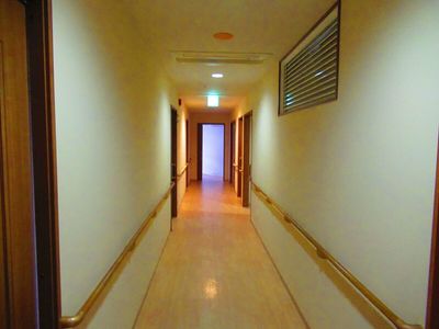 まっすぐな廊下の両サイドに手すりが付き、ブラウンの木製のドアも付いている。