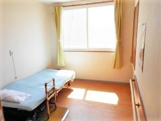 介護用ベッドがひとつだけ置いてある小さな居室の様子。手すりが付いている壁