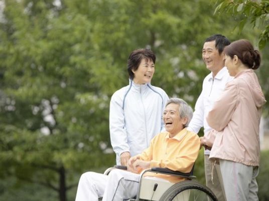車いすに乗った男性と寄り添う介護スタッフ