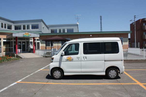 スロープ付きの厳顔と手前に施設用の車が写っている施設の全景