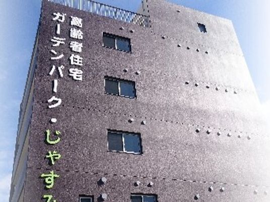 グレーの外壁の６階建ての建物の外壁には住宅名が書かれ、日当たりのいい場所に建っている。