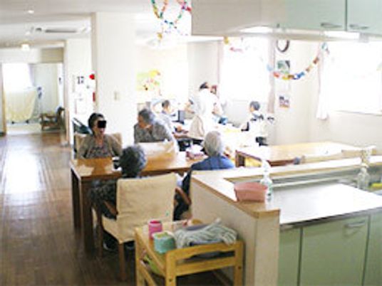 明るいリビングダイニングにはたくさんの窓が付き、天井からは手作りの輪っかの飾りがぶら下がり、入居者は思い思いの場所で過ごしている。