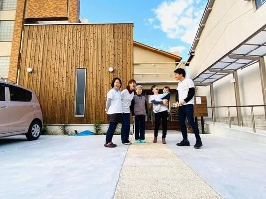 車いすに乗った男性入居者と屋外での散歩を楽しむ女性スタッフ。自然あふれる環境。