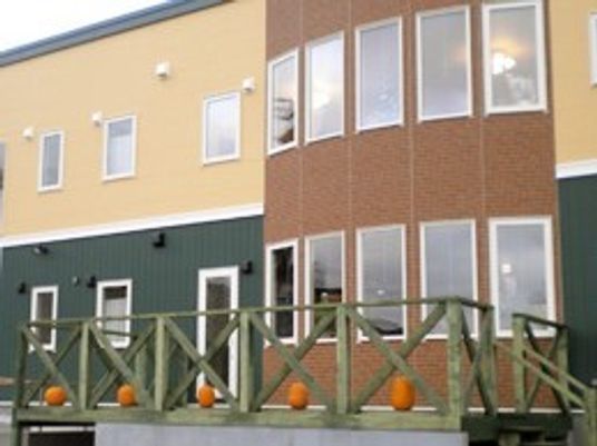 ブラウン系の2階建ての建物にはウッドデッキが付き、窓もたくさん設置されている。