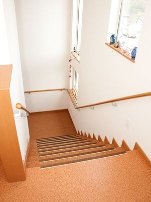 手すりが両サイドに設置された階段はブラウンで、壁は白。