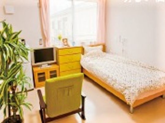 ベッドや観葉植物、テレビやいすなどが置かれた居室には大きな窓が付き、明るい雰囲気。
