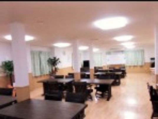 黒いダイニングテーブルが並んだ食堂は天井が高く、観葉植物も置かれている。