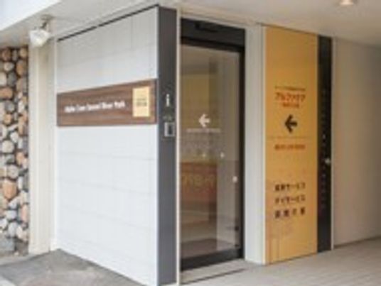 エントランスには段差がなく、外壁には住宅名が書かれている。併設事業所の案内もある。