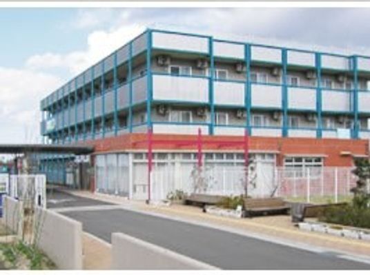 白を基調とした4階建ての建物には各フロアにベランダがあり、ブルーのラインが入っている。