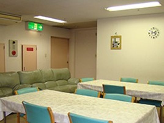 机と椅子が数組、その横にソファが並んでいる施設内の共有スペースの様子